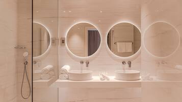 A modern bathroom with three round mirrors, two sinks, and a shower.
