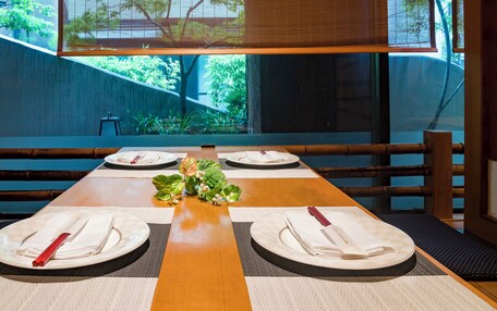 A dining table set for four with placemats, plates, and folded napkins.