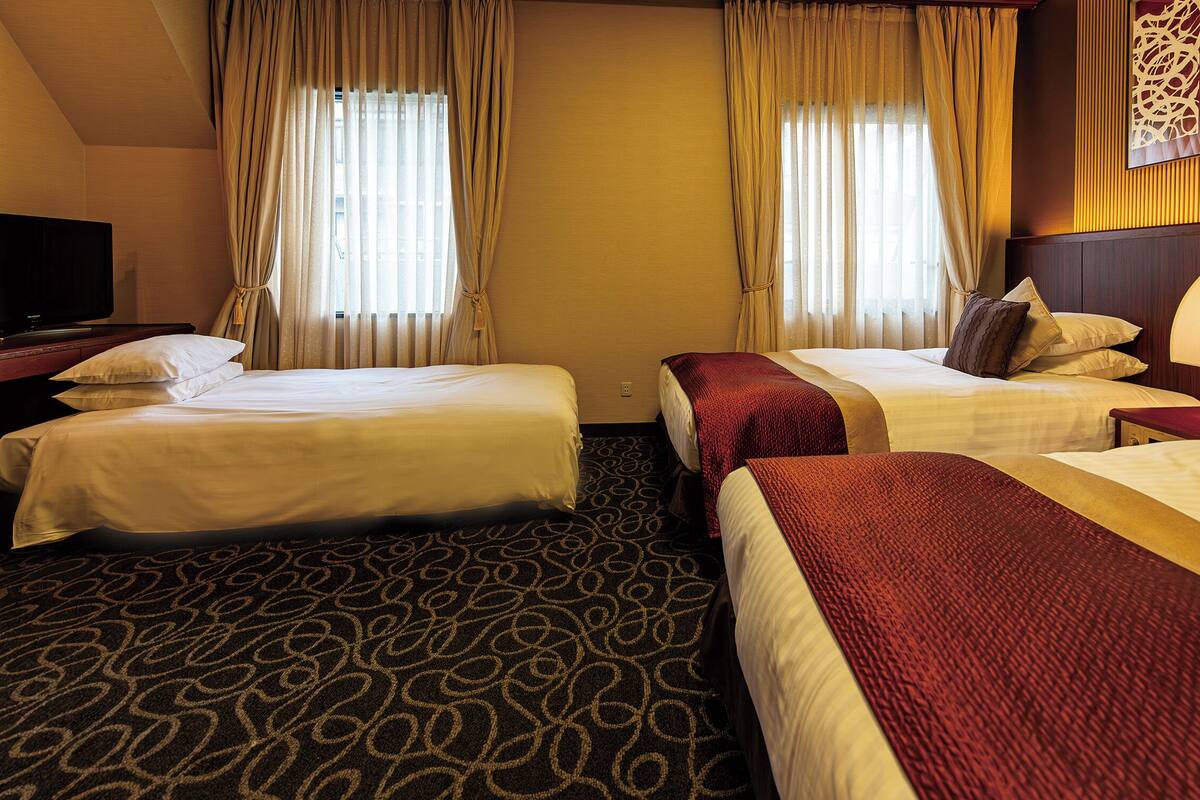 Una habitación de hotel con dos camas, televisión y lámpara.