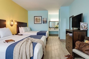 Een hotelkamer met twee bedden, een televisie, een bureau, een spiegel en een kledingkast.