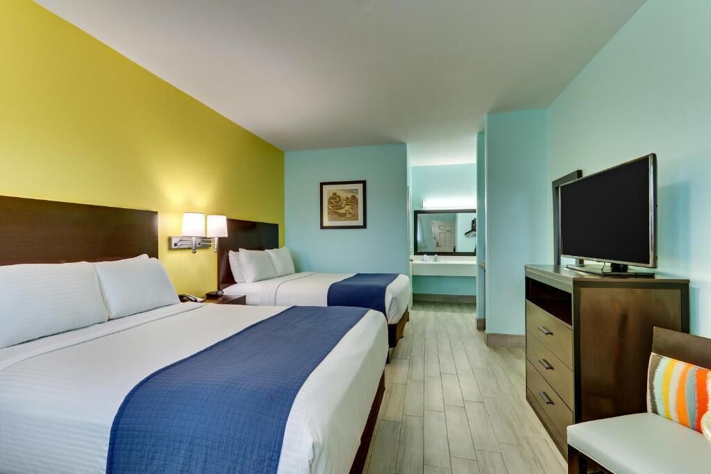 Una habitación de hotel con dos camas, televisión, escritorio y una silla.