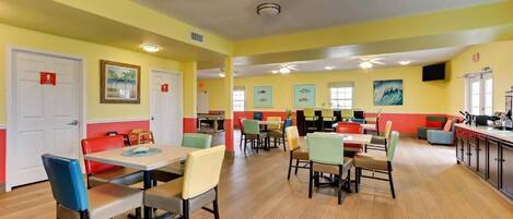 Un espace repas avec des tables et des chaises, un ventilateur de plafond et des œuvres d’art accrochées aux murs.