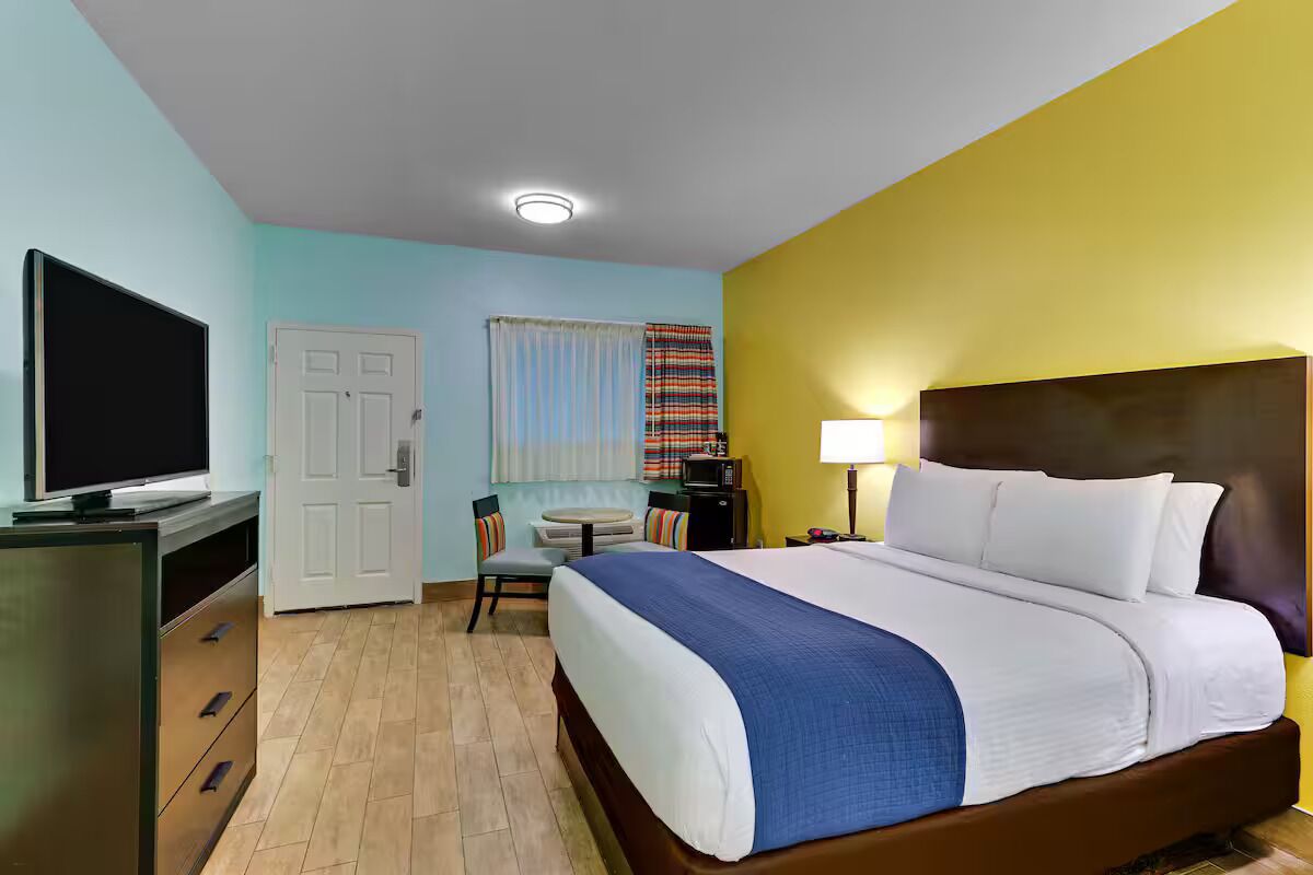 A hotel room with a bed, a TV, a desk, and a chair.