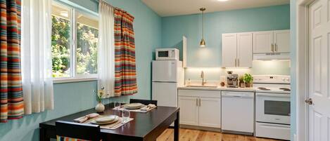 A compact kitchen with white cabinets, a microwave, a dishwasher, and a stove.