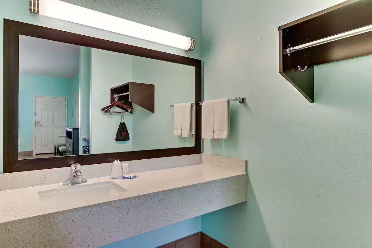 A bathroom with a white sink, a large mirror, and a towel rack.