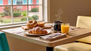 Een ontbijttafel met croissants, een bagel en een glas sinaasappelsap.