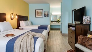 Hotelkamer met twee bedden, een televisie, een dressoir, een spiegel en een nachtkastje met een lamp.