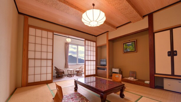 A traditional Japanese room with tatami flooring, a low table, and a view of mountains through a sliding door. - Nikko Sansui (Nikko)