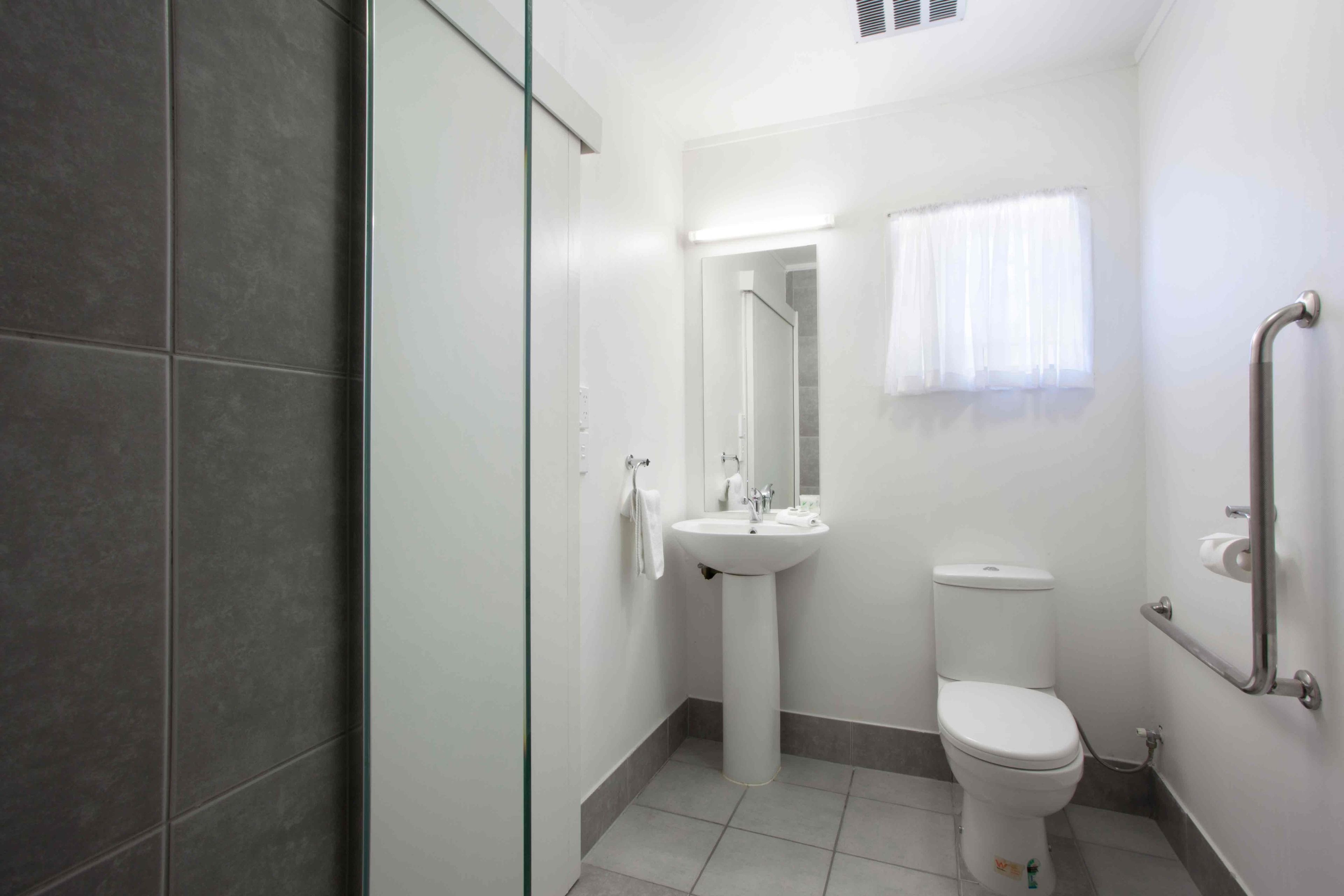 A compact bathroom with a toilet, sink, and glass shower enclosure.