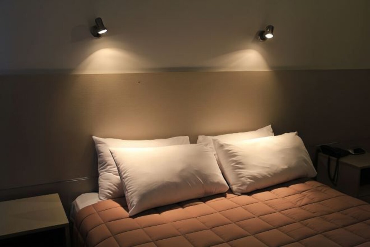 Une chambre à coucher avec un lit, deux lampes de chevet et une table de nuit.