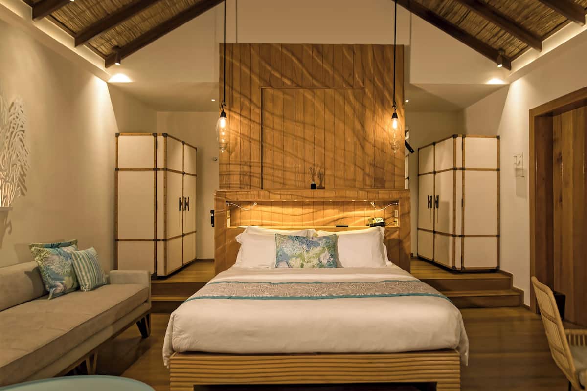 Un dormitorio con una cama grande, un sofá y armarios de madera.