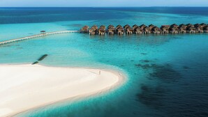 An aerial view of overwater bungalows with a sandy beach and clear turquoise waters. - Constance Moofushi All Inclusive (Moofushi Island)
