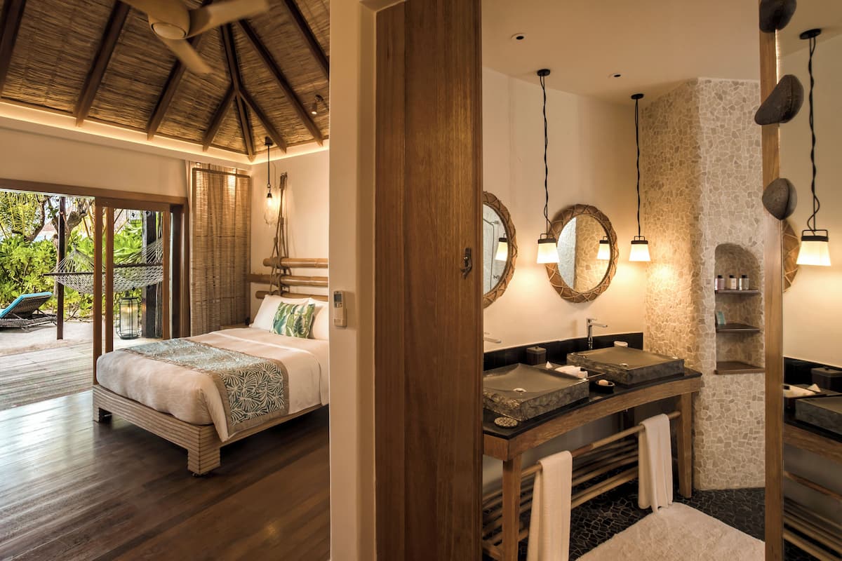 Un dormitorio con cama, un baño con lavabo y espejo, y vistas al exterior.