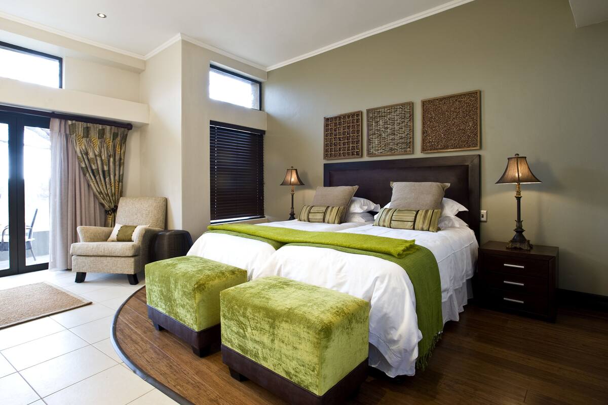 A modern bedroom with a large bed, two bedside tables, a chair, and a view of the outdoors.