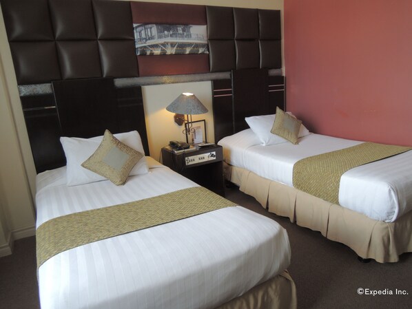 A hotel room with two beds, a nightstand, a lamp, and a picture on the wall. - The Bellavista Hotel (Lapu-Lapu)