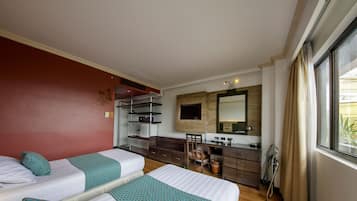 Una habitación de hotel con dos camas, una kitchenette, un espejo y una ventana.