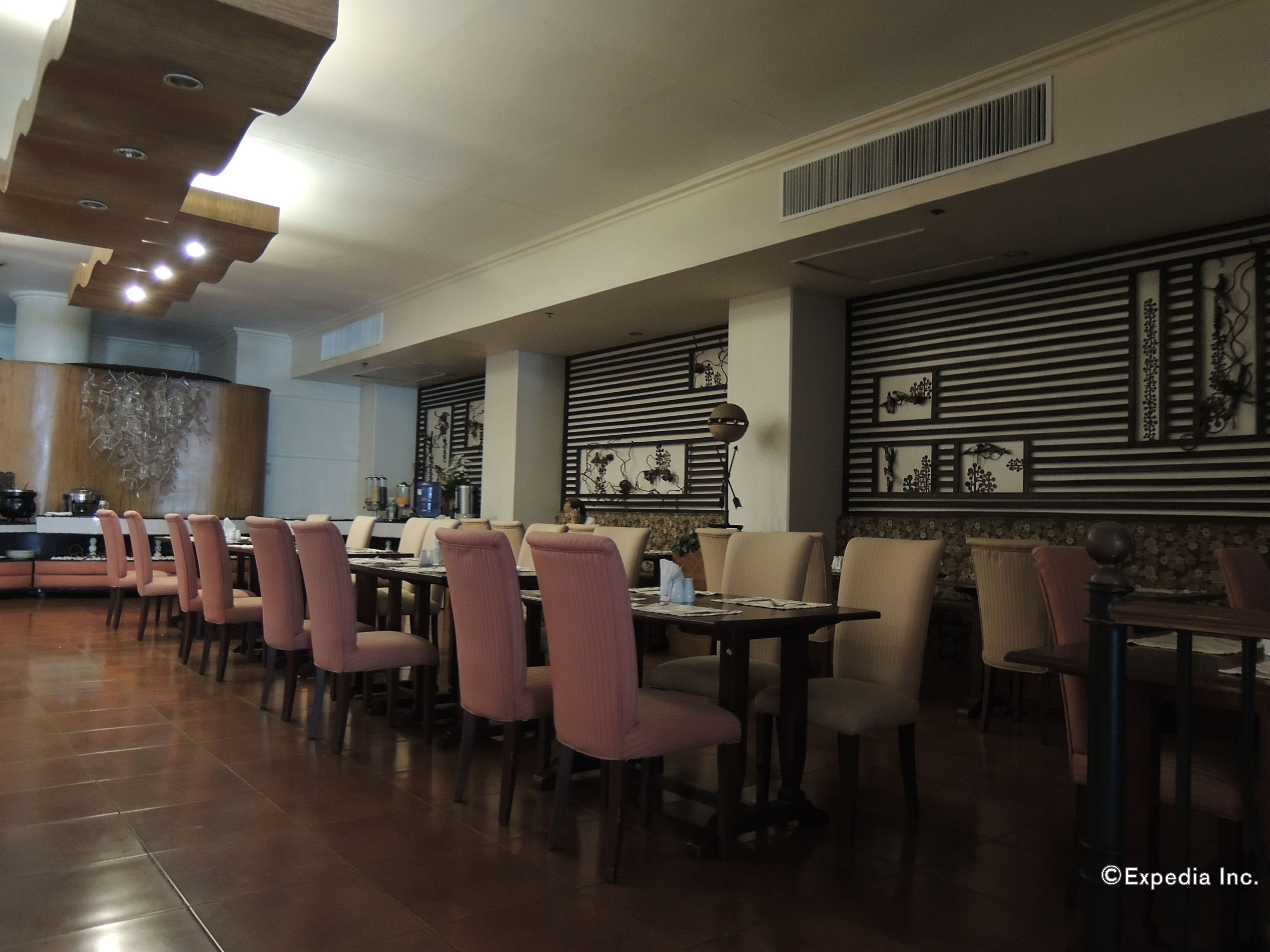 Un restaurante con una barra alargada, varias mesas y sillas.
