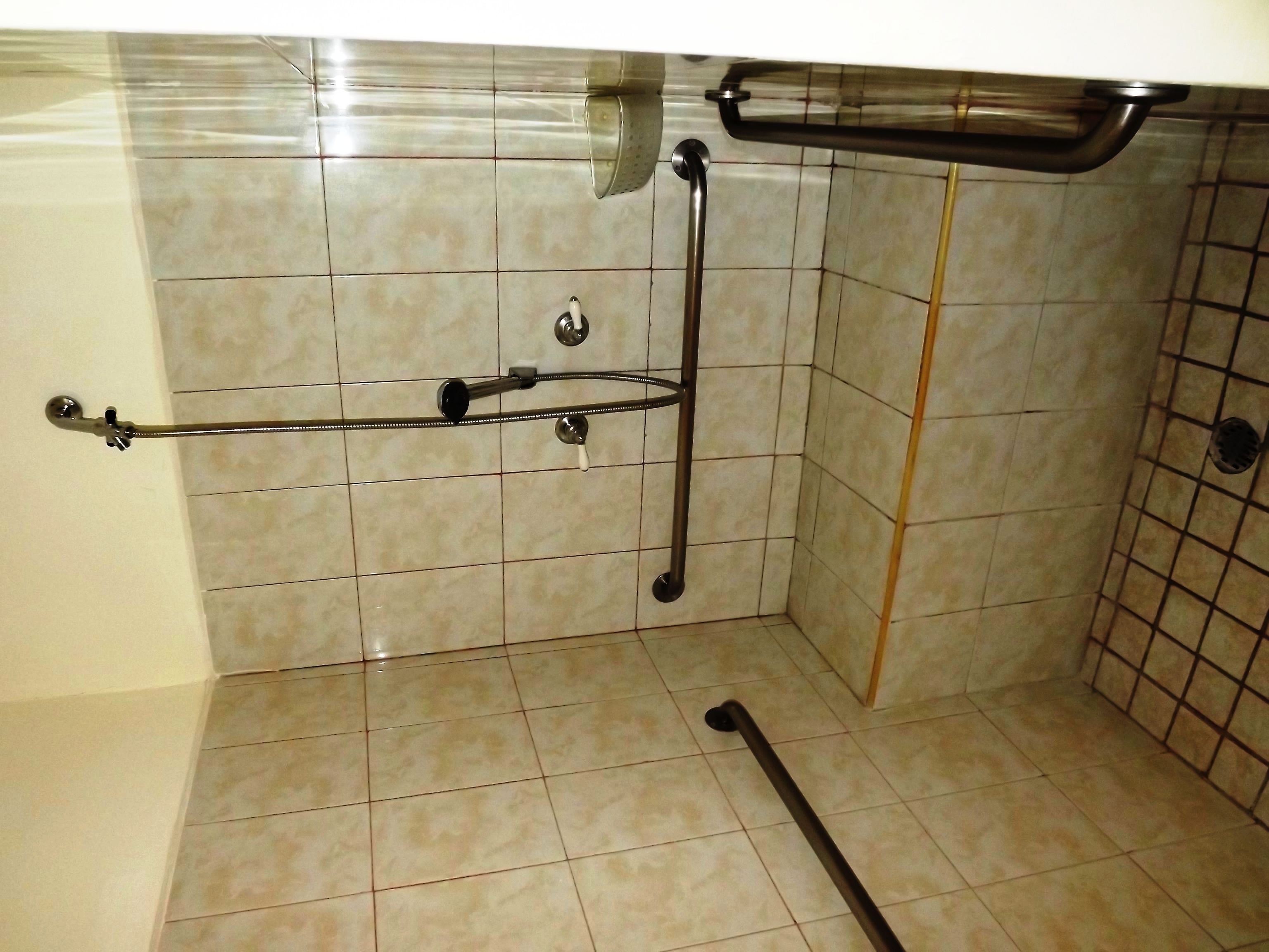 A bathroom with a shower area, tiled walls, and a towel rack.