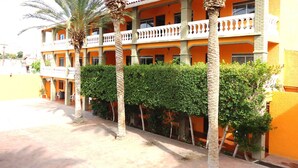 Un edificio de varios pisos con balcones, palmeras y un patio.