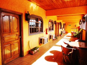 A corridor with wooden doors, arched windows, and potted plants. - La Hacienda de la Langosta Roja (San Felipe)