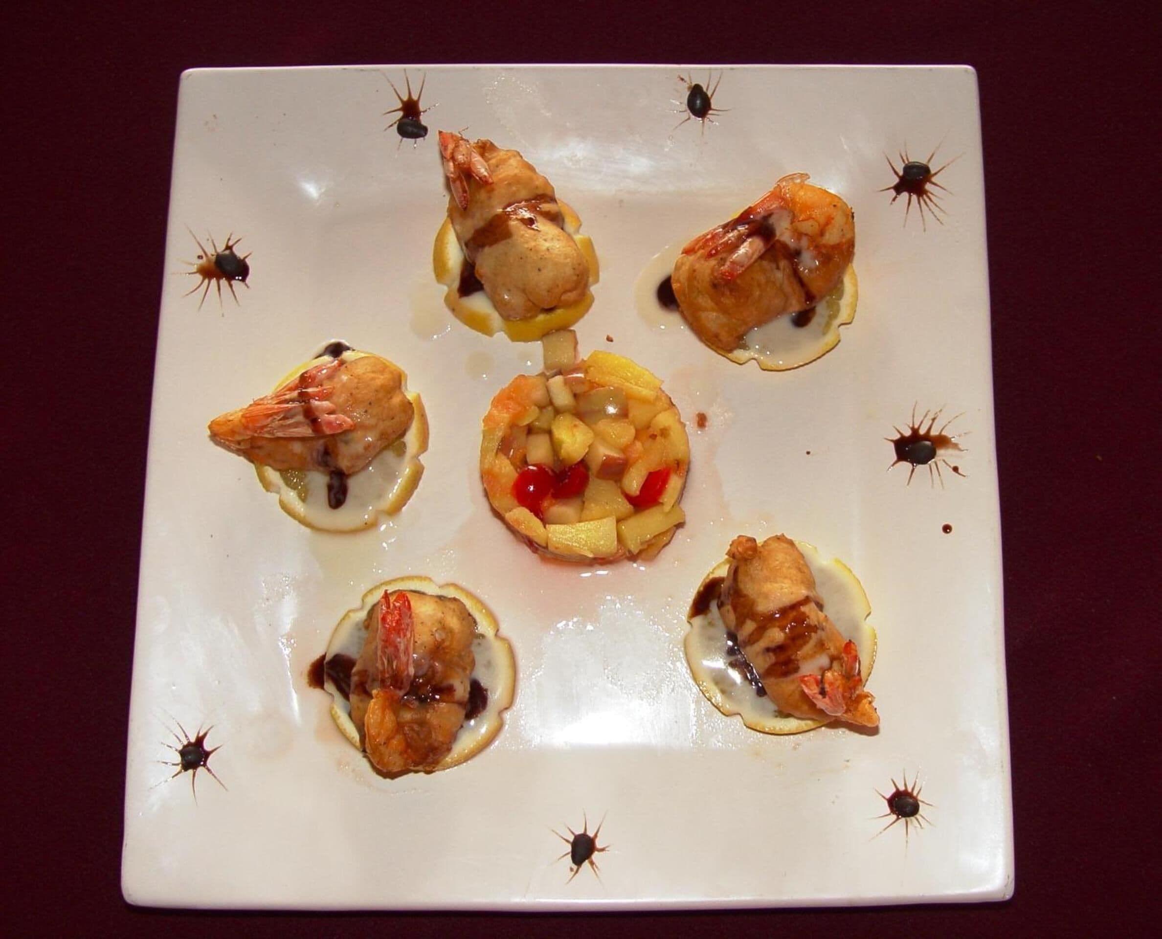Un piatto quadrato con cibo, tra cui gamberi e frutta.