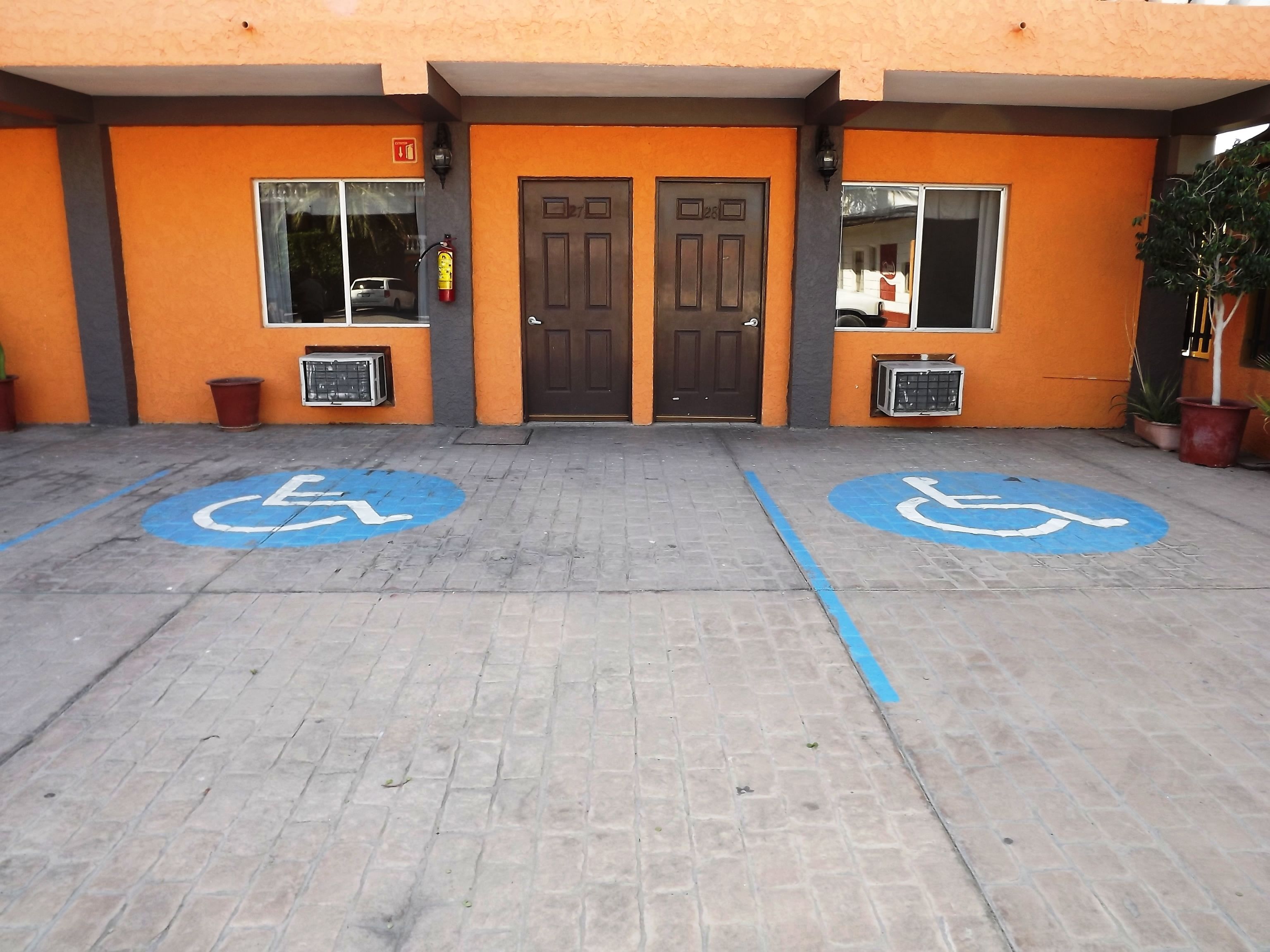 A building entrance with two wheelchair-accessible parking spaces marked on the pavement.