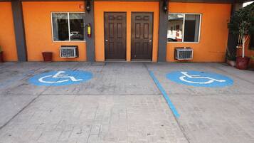 A building entrance with two wheelchair-accessible parking spaces marked on the pavement.