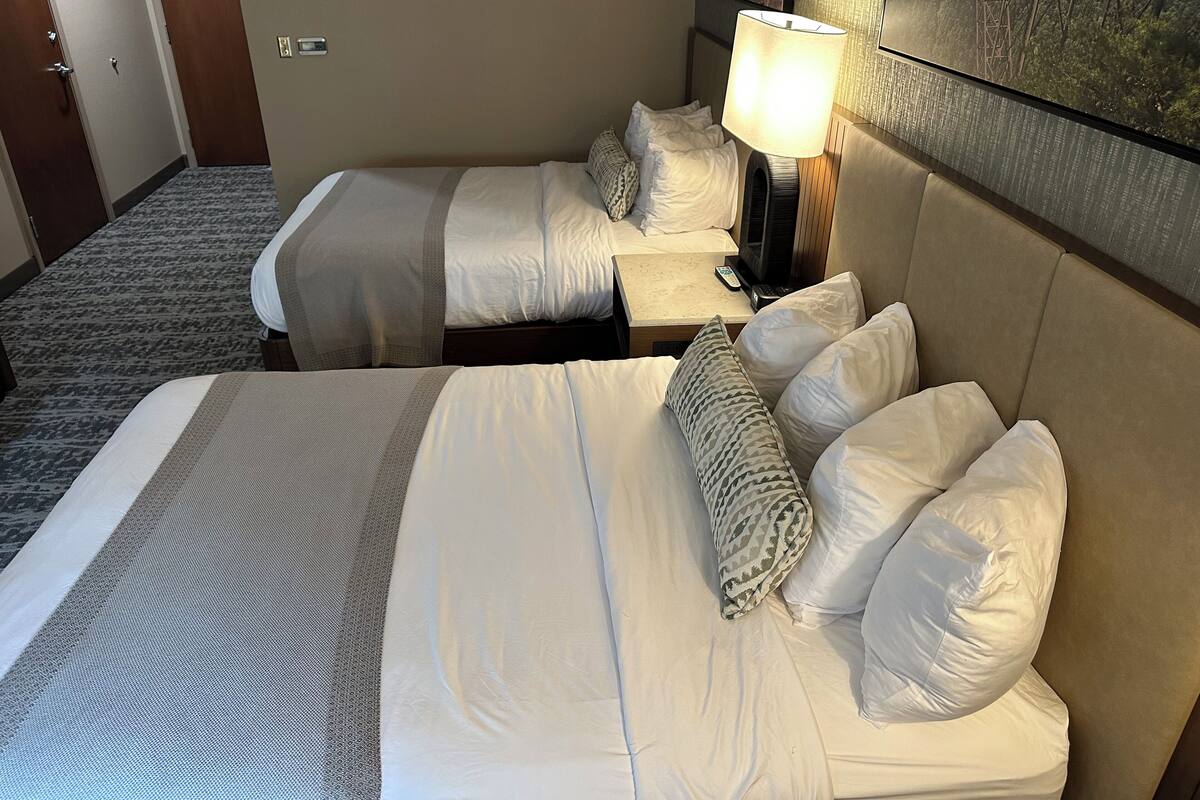 Ein Hotelzimmer mit zwei Betten, einem Nachttisch mit Lampe und einem Bild an der Wand.