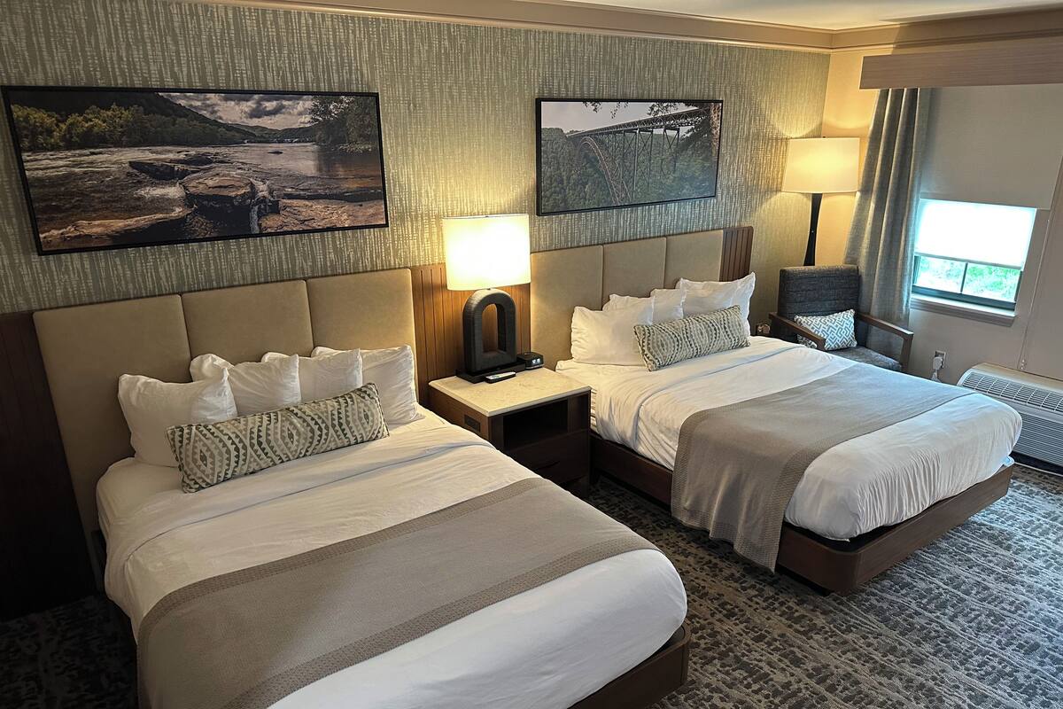 Ein Hotelzimmer mit zwei Betten, einem großen Fenster und Bildern an den Wänden.