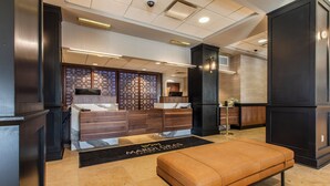 Een moderne lobby met een receptiebalie, een zithoek en een decoratieve wand.