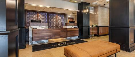 Een moderne lobby met een receptiebalie, een zithoek en een decoratieve wand.