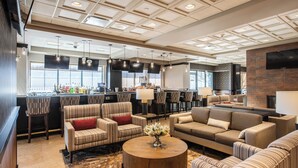 Een moderne loungeruimte met gestreepte banken, een ronde salontafel en een bar met uitzicht.