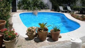 A swimming pool with a white wall and potted plants around it. - El Soto de Roma (Fuente Vaqueros)