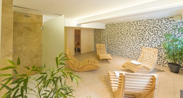 A modern spa area with wooden loungers, a tiled floor, and a patterned wall. - Ostend Hotel (Ostend)