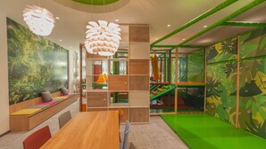 A children's play area with a slide, seating, and a large wall mural. - Ostend Hotel (Ostend)
