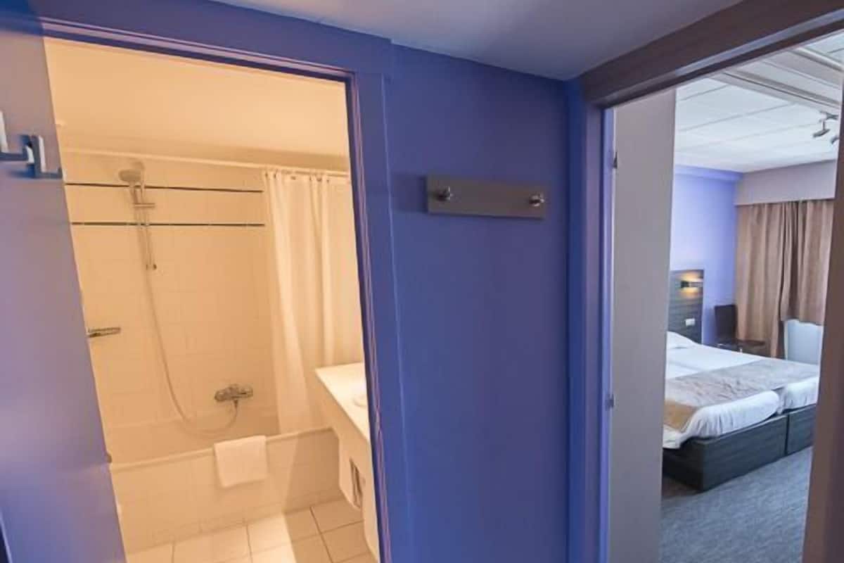 A hotel room with a shower, a bed, and a bathroom.