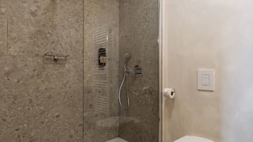 Une salle de bain moderne avec une douche à parois de verre, des toilettes et un porte-serviettes.