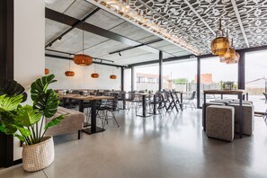 A modern dining area with high ceilings, exposed beams, and large windows. - C-Hotels Zeegalm (Middelkerke)