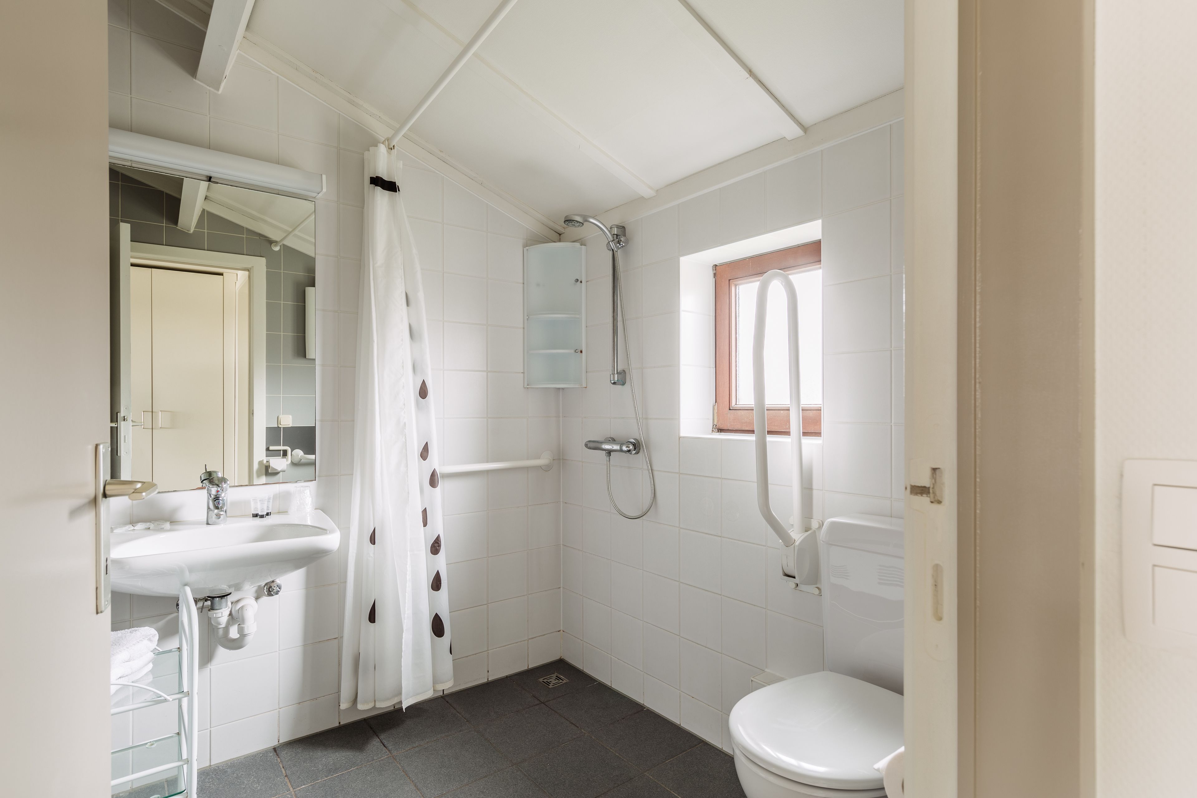 Un baño con lavamanos, inodoro y ducha blancos.