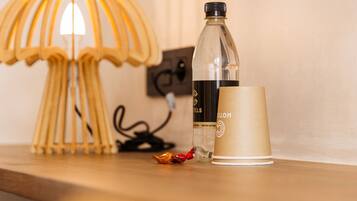 A wooden table with a lamp, a bottle, and a cup.