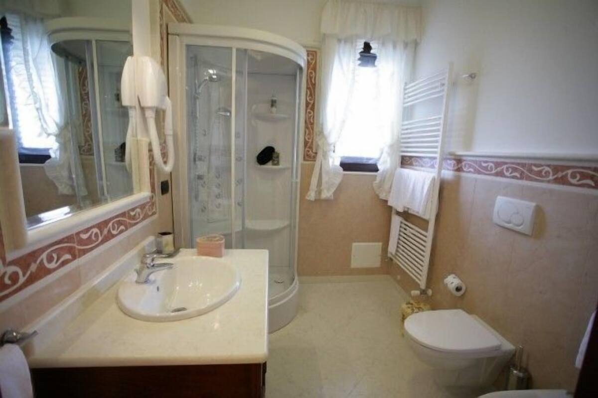 Baño con lavamanos, inodoro, ducha y espejo.