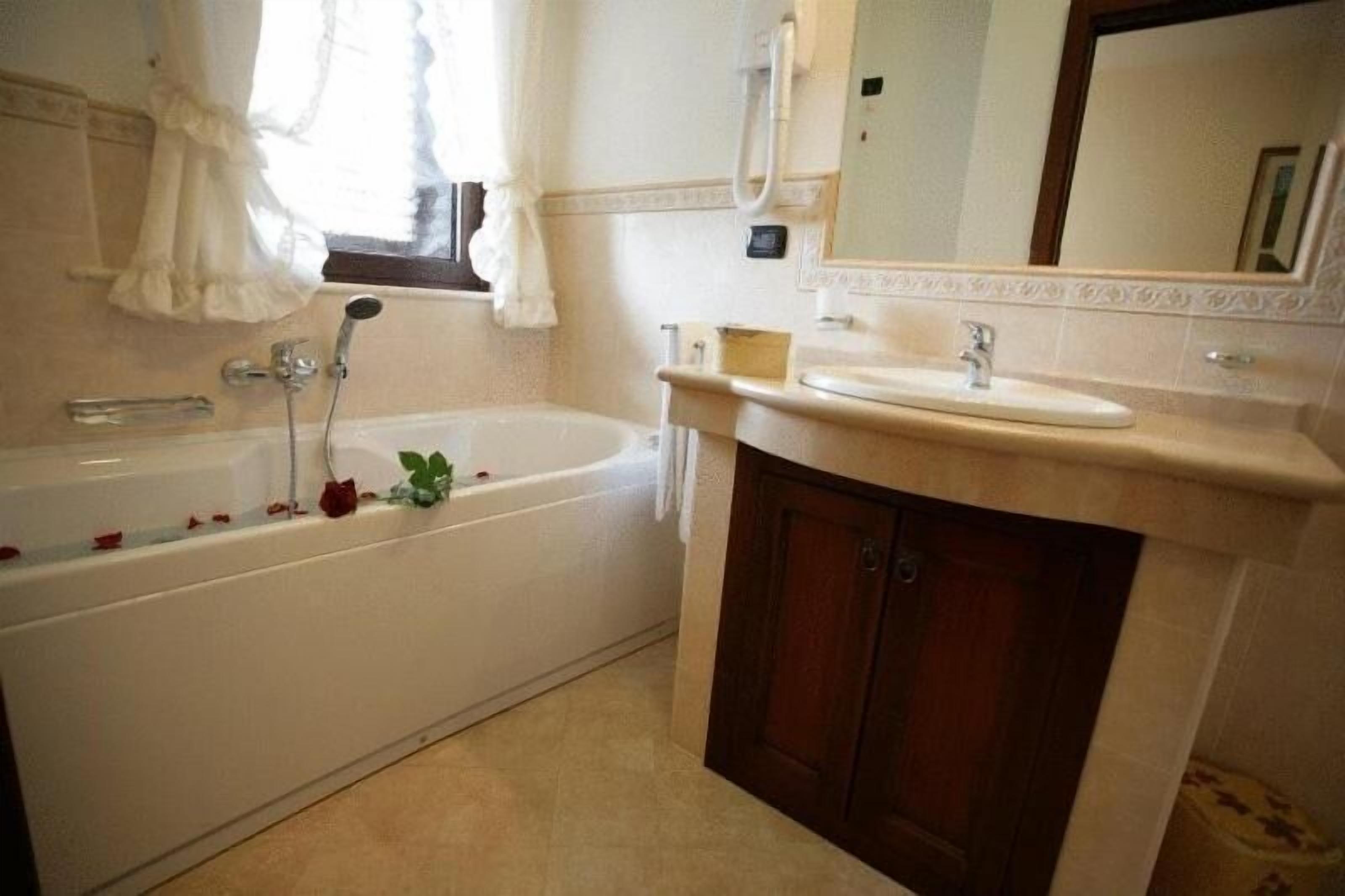 A bathroom with a bathtub, a sink, and a mirror.