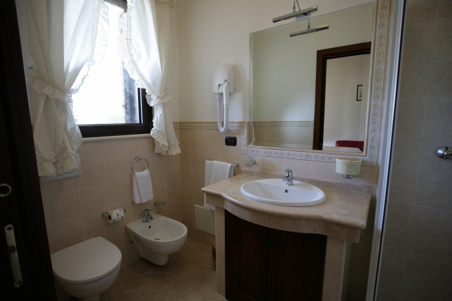 Une salle de bain équipée de toilettes, d’un bidet, d’un lavabo et d’un miroir.