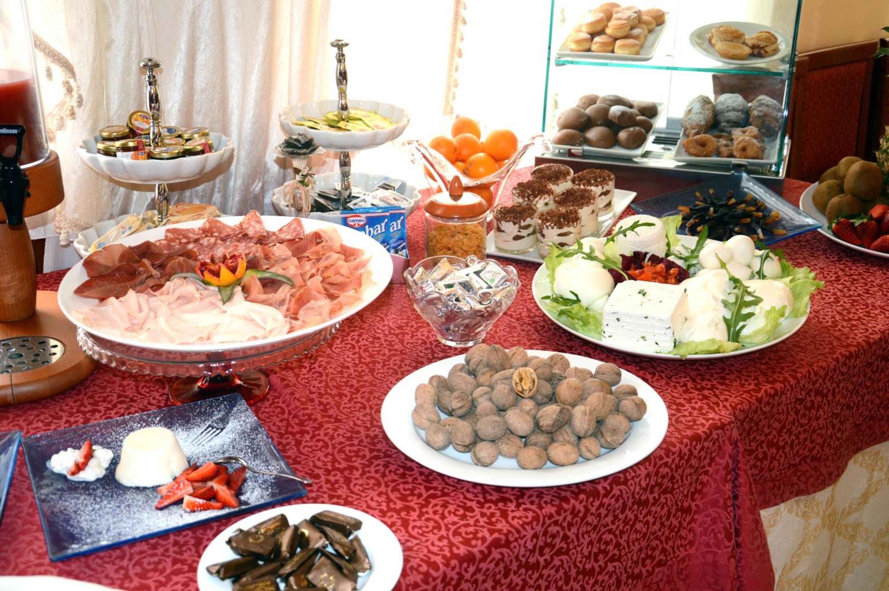 A buffet with various food items including meats, cheeses, and pastries.