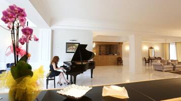Un vaste salon agrémenté d’un magnifique piano à queue, d’un coin repas et d’un aménagement intérieur moderne.