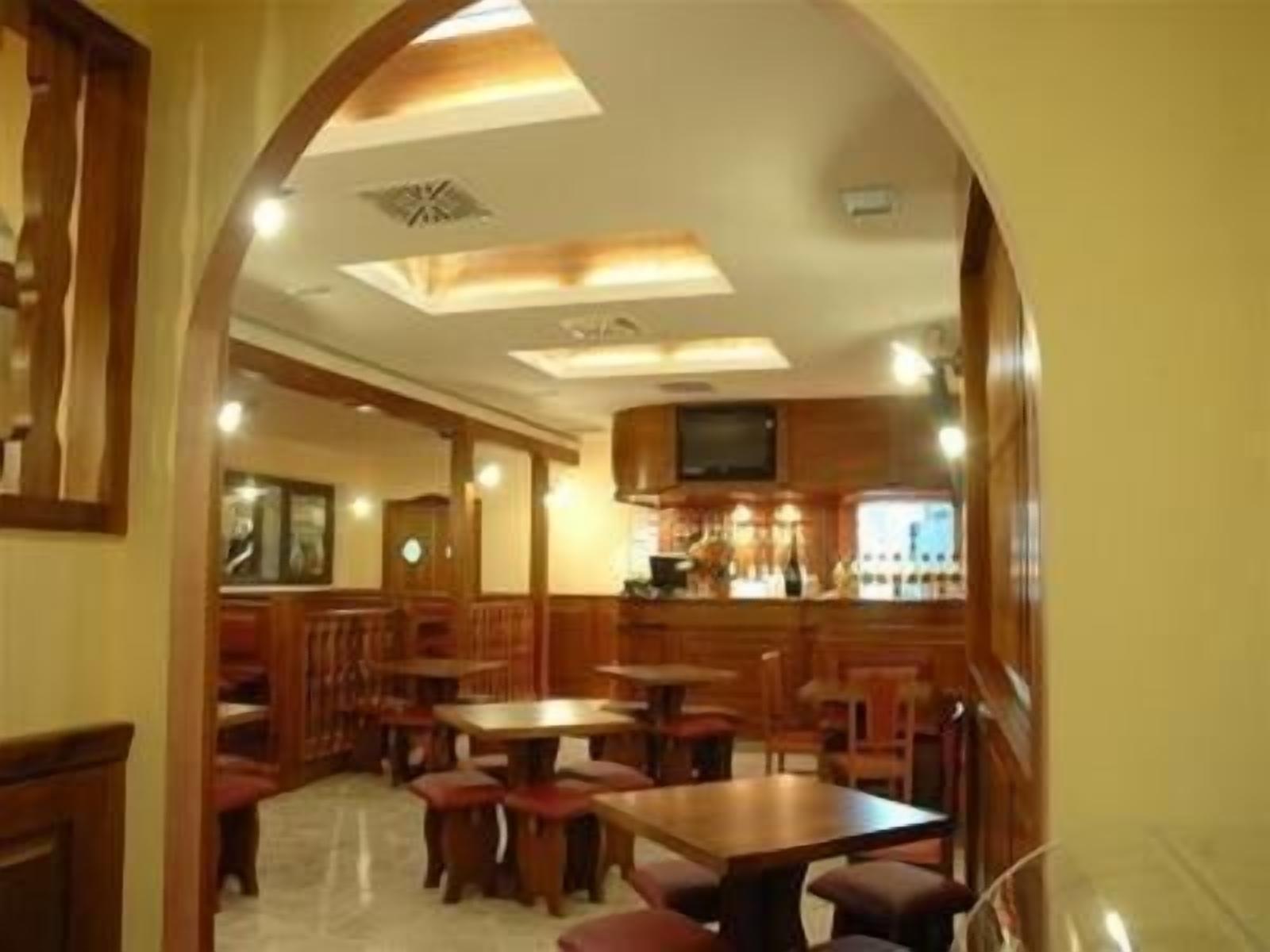 Un restaurante con muebles de madera, una zona de bar y un techo con tragaluces.