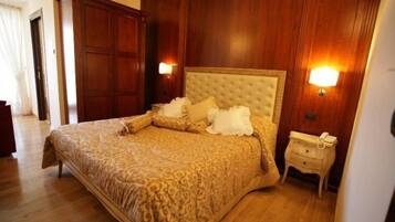 Una camera da letto con un letto grande, pannelli in legno, due lampade sui comodini e un comodino con un telefono.