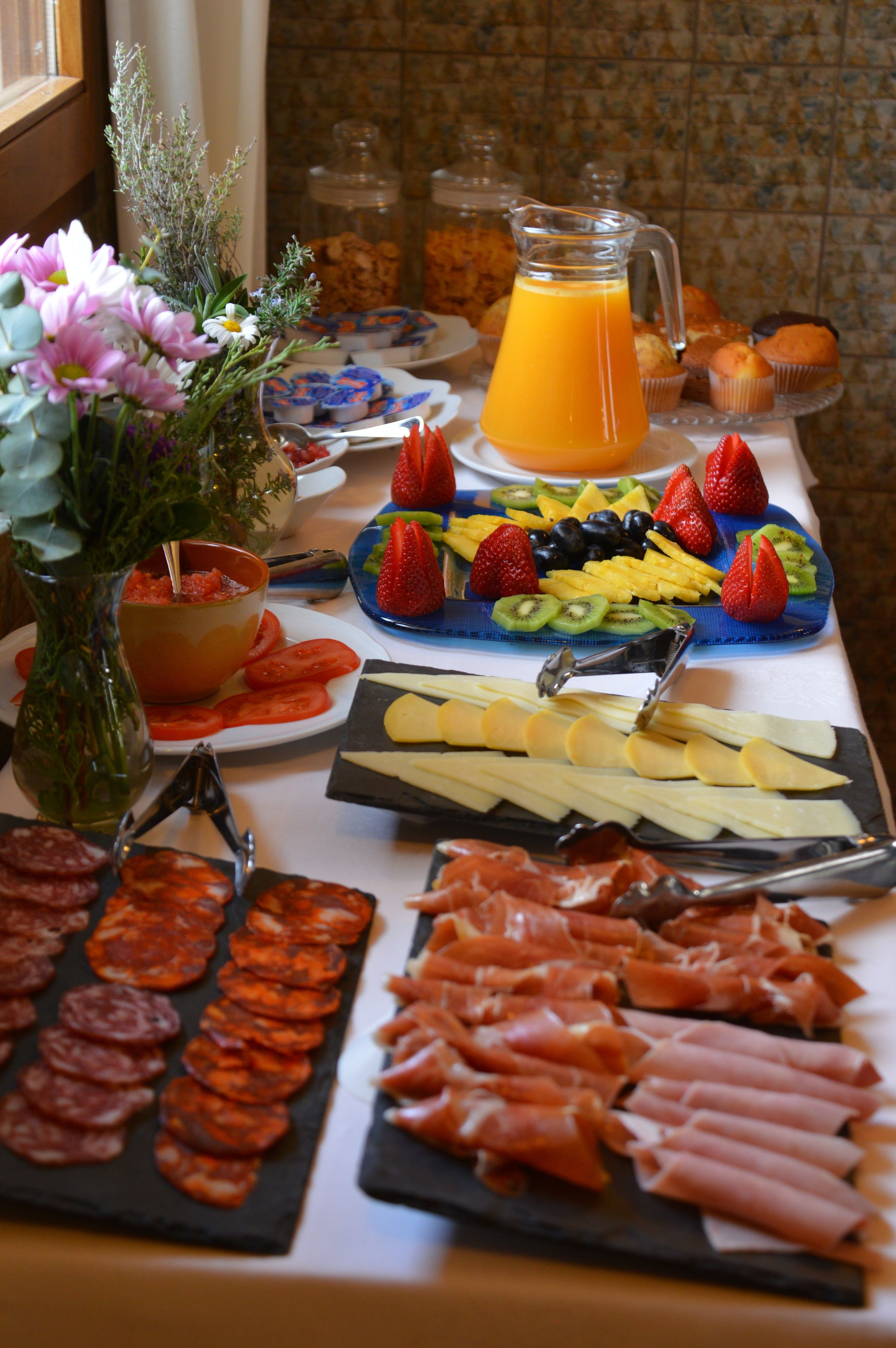 Una mesa de buffet con diversas opciones de comida, como frutas, quesos y carnes.