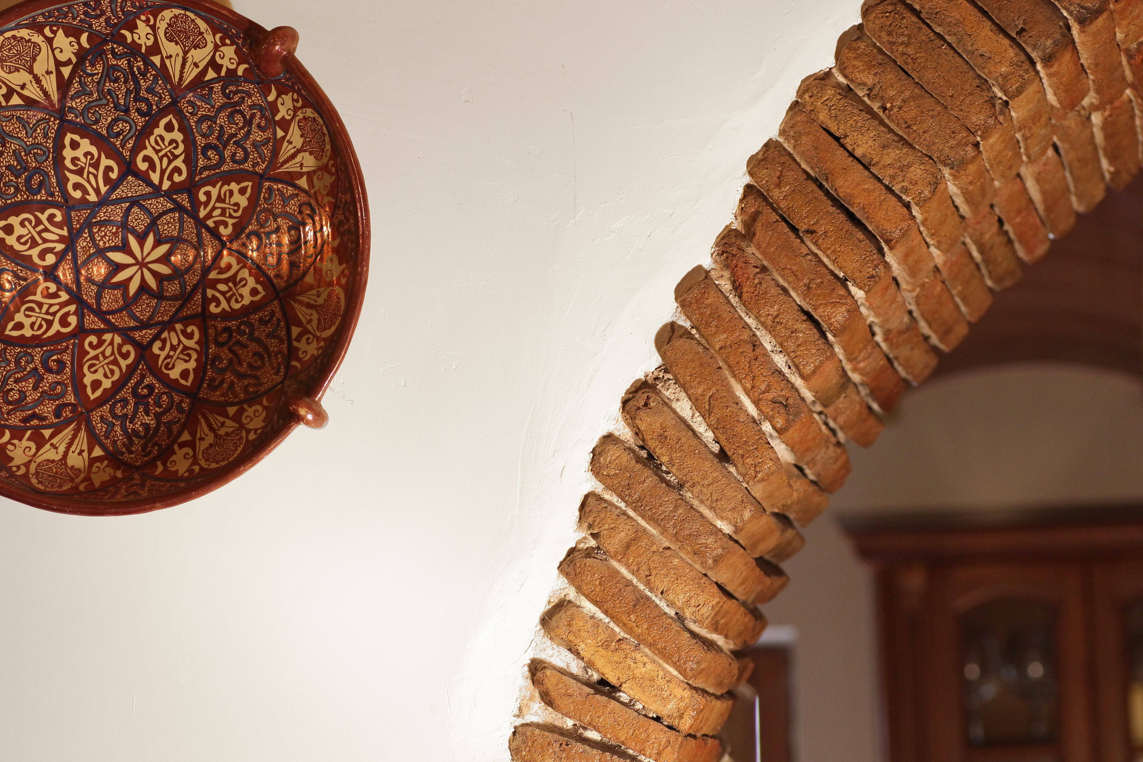 A spiral staircase with a brick pattern and a decorative plate with intricate designs.