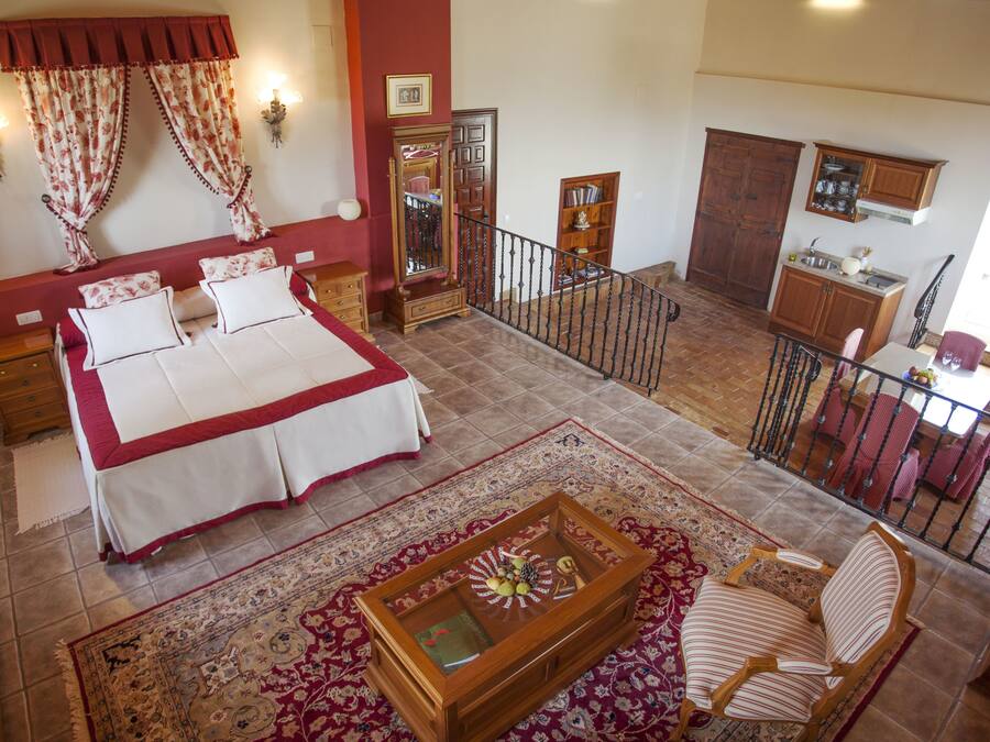 A hotel room with a bed, a wooden coffee table, a chair, a desk, a wardrobe, and a balcony with a railing.